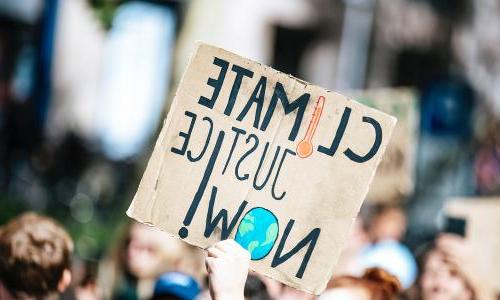 Activist holding up a climate justice now sign